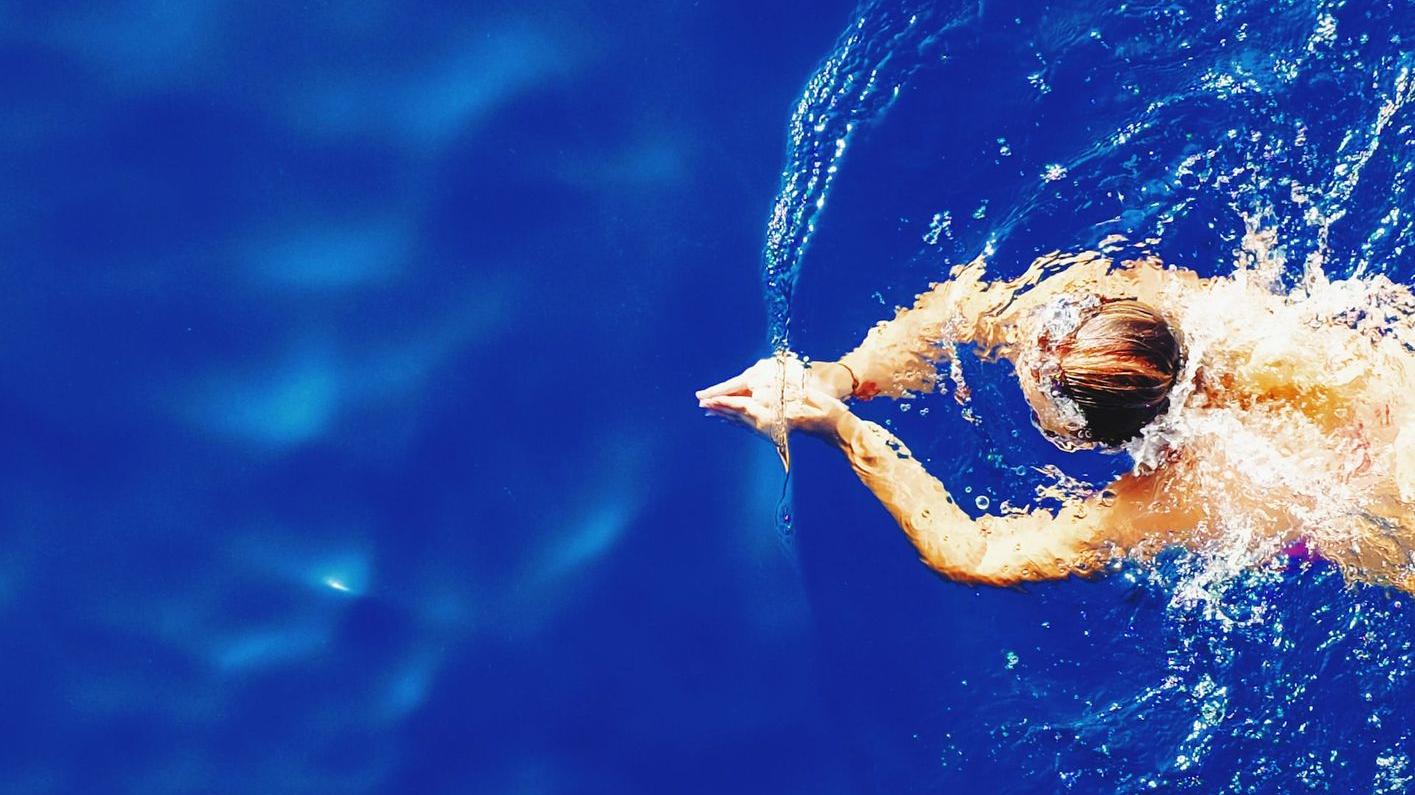 close-up photography of woman swimming on calm water
