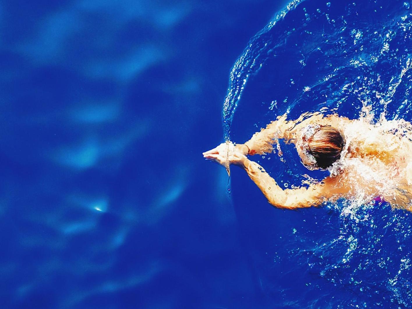 close-up photography of woman swimming on calm water